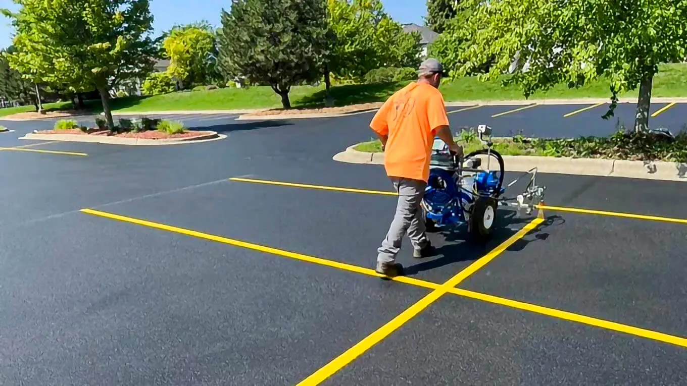 Vinco Pavement Co. crew member line striping a commercial parking lot
